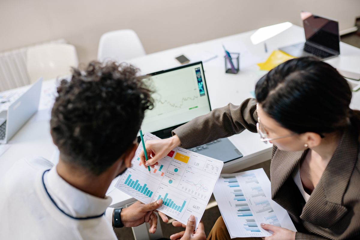 Two colleagues reviewing analytics dashboards at a desk in a bright office