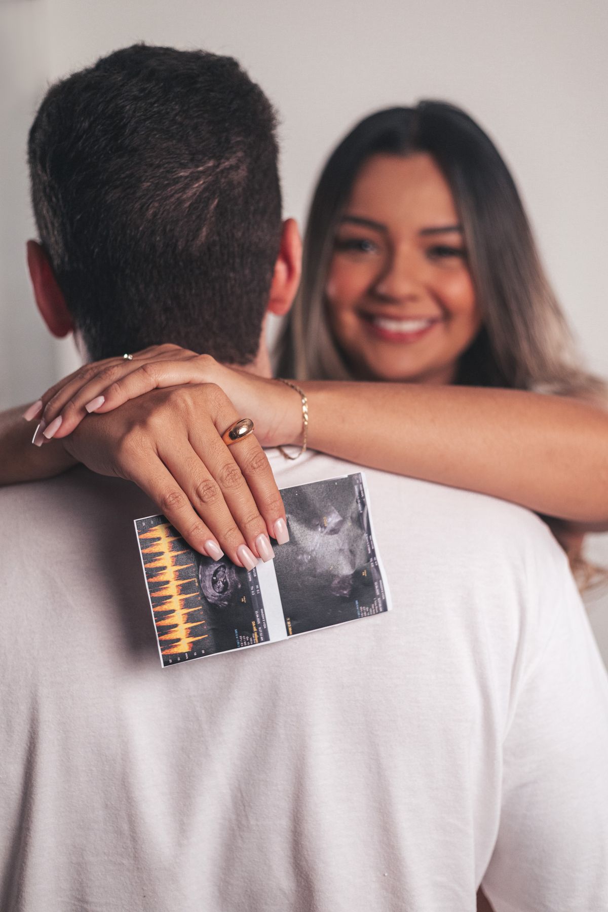A couple embracing while holding a printed ultrasound photo