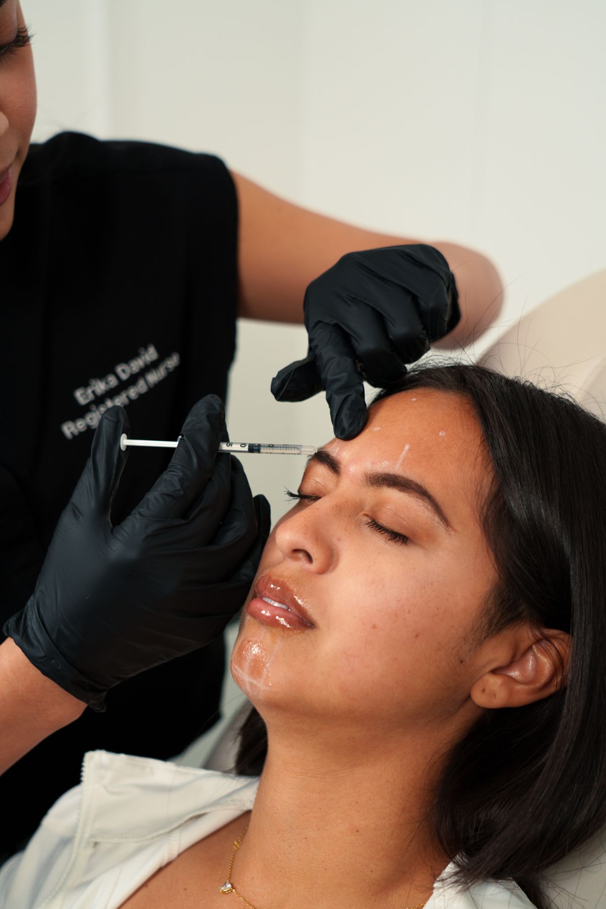 A nurse injector performing a treatment in a bright med spa