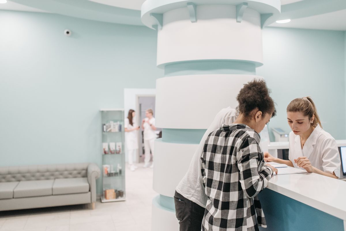 Patients checking in with a receptionist at a bright clinic front desk